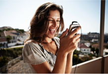 Swisscom führt «Easy Travel Insurance Day» für Privatkunden ein Eine junge Frau schaut aufs Hanhdy.